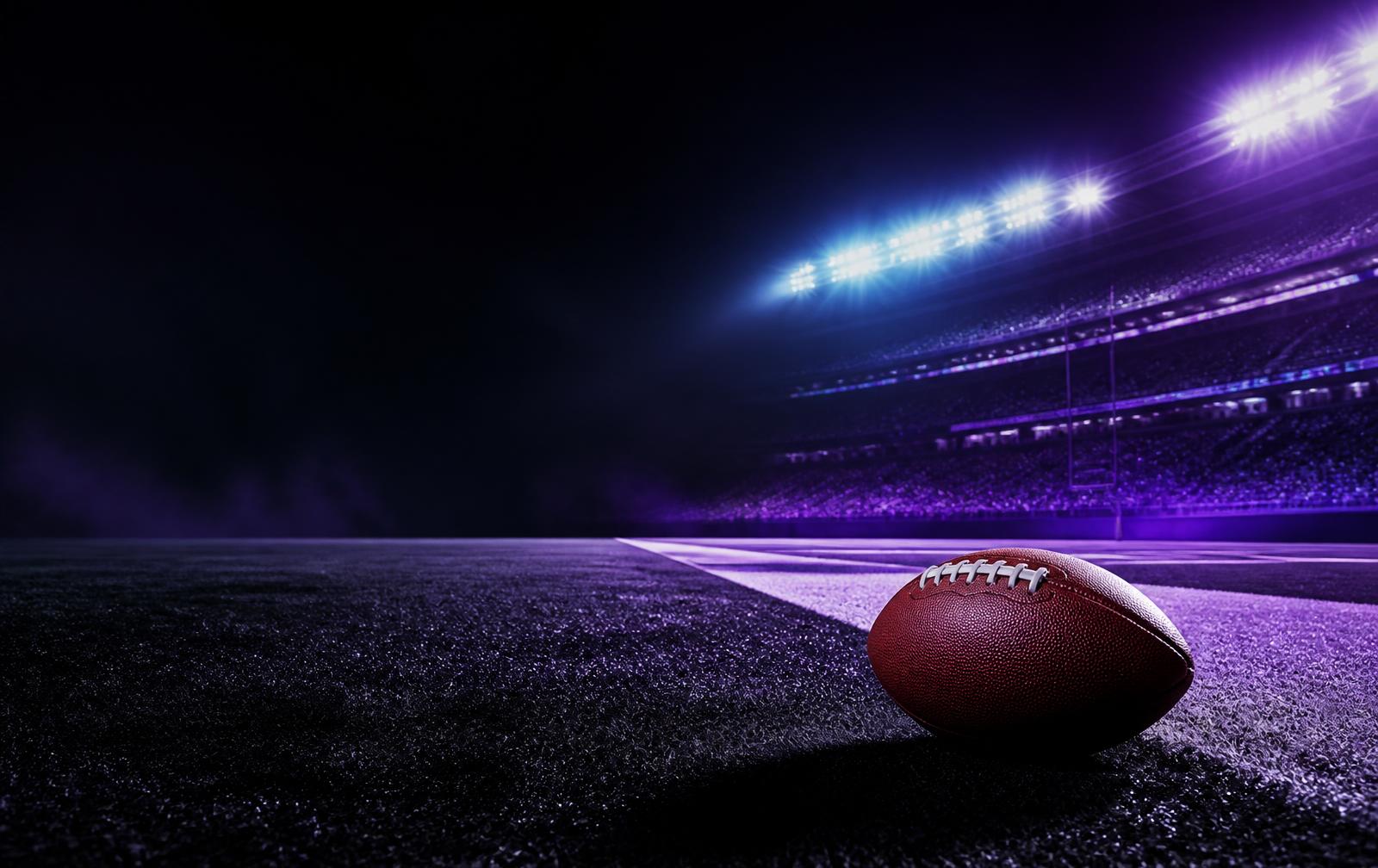 Football on the field in a purple-lit stadium